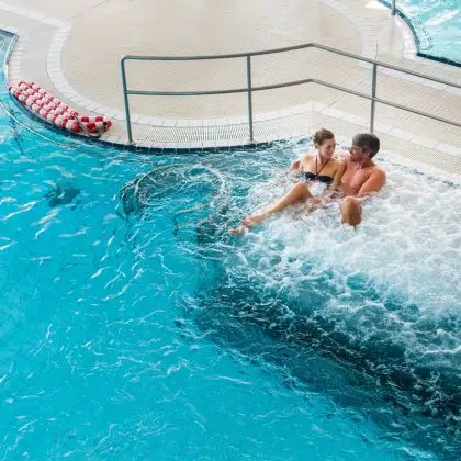 Couple in thermal wellness spa on water massage enjoying the treatment